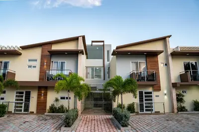 an apartment building with palm trees in front of it at La Isla Royal - Abismo Celeste in Miches