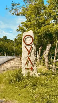a stone statue in the grass next to a road at OYA New Earth Luxury Romantic Glamping with Private Outdoor Bath in Jamao al Norte