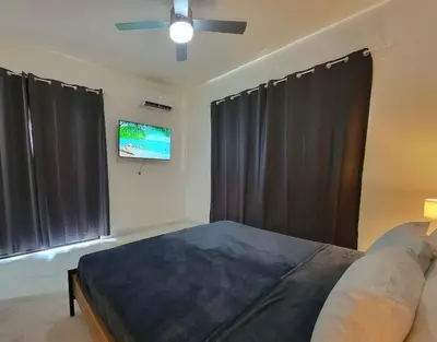 a bedroom with black curtains and a tv and a bed at Villa Serene Breeze Private Pool Sosua Ocean Village in Sosúa