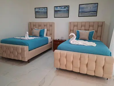 a bedroom with two beds and a couch at Hermosa villa familiar cucu's home beach in Río San Juan