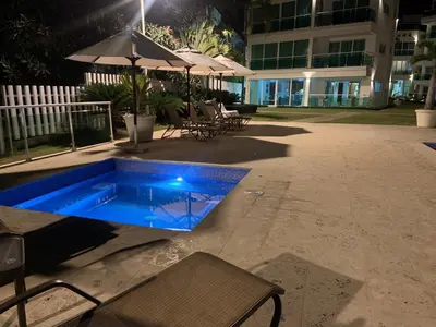 a swimming pool at night with chairs and an umbrella at Luxury Oceanfront Condo in Sosúa