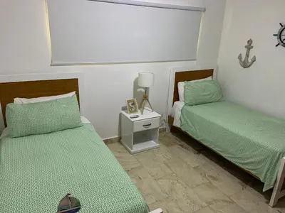 a bedroom with two beds and a night stand with a lamp at Luxury Oceanfront Condo in Sosúa