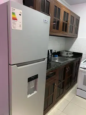 a white refrigerator in a kitchen with wooden cabinets at Style and comfort in downtown Santiago in Santiago de los Caballeros