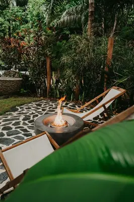 a fire pit on a patio with chairs and trees at OYA New Earth Private Jungle Cabin with Individual Campfire in Jamao al Norte