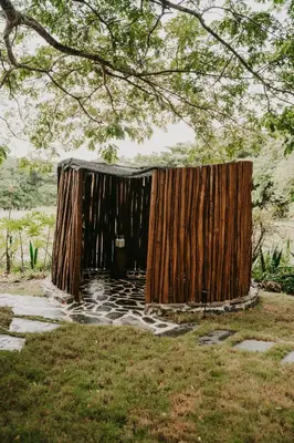 a wooden structure with a cover on the grass at OYA New Earth Private Jungle Cabin with Individual Campfire in Jamao al Norte