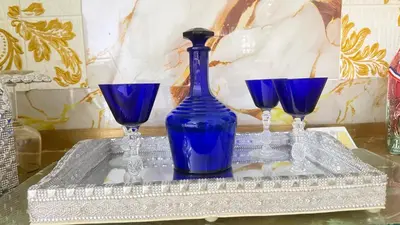 a blue glass bottle and three wine glasses on a table at Apartamento en Santo Domingo Pablo mella morales in Hato Nuevo