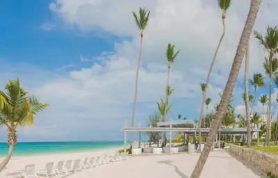 a beach with chairs and palm trees and the ocean at Playa Privada | Terraza & Piscina • WiFi Rápido in Punta Cana