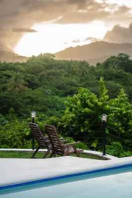 two chairs sitting next to a swimming pool with mountains in the background at Villa Playa Colorada Eco-Luxury Beachfront Retreat in La Colmena