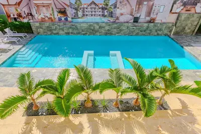 a swimming pool with palm trees in front of a house at Esprit Caribbean Bayahibe by Caribbean Paradise Rentals in Bayahibe