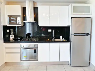 a kitchen with white cabinets and a stainless steel refrigerator at Con Estilo Soha II in Colorado