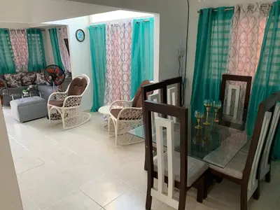a living room with green curtains and a table and chairs at Seaside Elegance in Baní