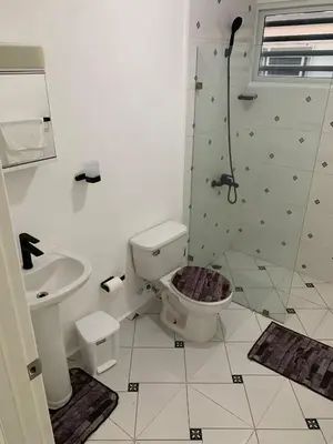 a bathroom with a toilet and a shower and a sink at Seaside Elegance in Baní
