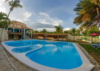a large swimming pool in a resort with palm trees at Hotel la Saladilla Beach Club in Santa Cruz de Barahona