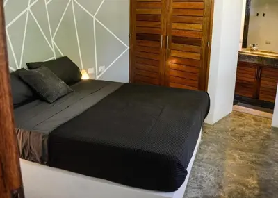 a bedroom with a bed and a wooden door at Nomadas 5 bdrs villa with private pool 2nd line to beach in Las Terrenas