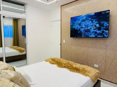 a room with a tv on a wall with a bed at Modern Apartment in Bayahibe in Bayahibe
