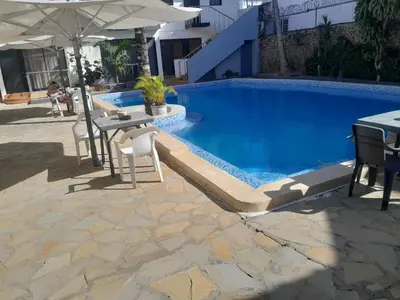 a swimming pool with a table and chairs and an umbrella at One bedroom apartment in the center with a pool in Sosúa
