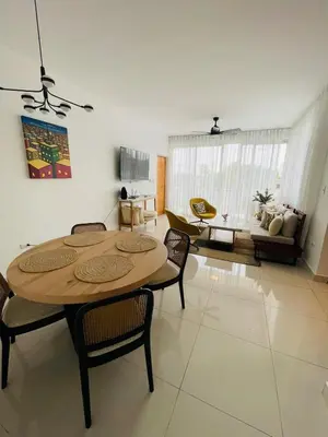 a living room with a wooden table and chairs at Oasis Residences, Modern 3BR Apartment with Pool in San Felipe de Puerto Plata