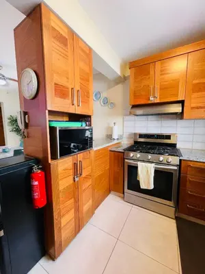a kitchen with wooden cabinets and a stove top oven at Modern 3BR with private pool near the beach in Puerto Plata