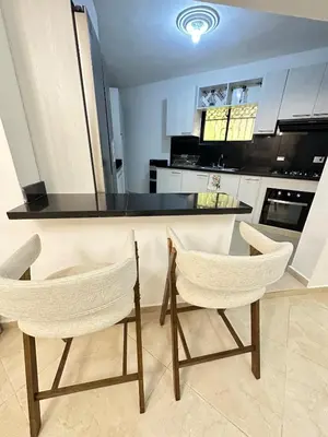 a kitchen with two chairs and a black counter top at Modern and fully equipped house in Samaná in Santa Bárbara de Samaná