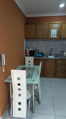 a kitchen with a glass table and white chairs at Mitaly Apartamentos 111 in Santo Domingo