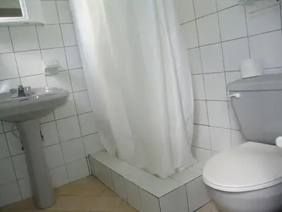 a bathroom with a toilet and a shower curtain at Waverider Apartments in Cabarete