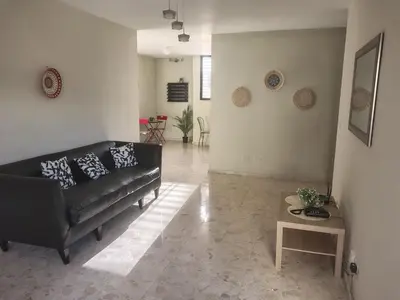 a living room with a black couch and a table at Double room with private bathroom in Santo Domingo
