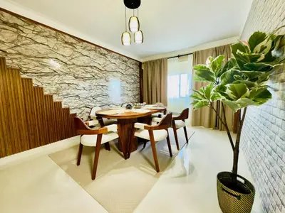 a dining room with a table and chairs and a stone wall at Luxurious 4 bedroom apartment near the beach in Ensanche Savica de Mendoza
