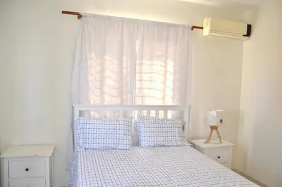 a bedroom with a white bed with a window at Comfortable Apartment, Torre Alta in San Felipe de Puerto Plata