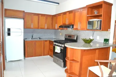a kitchen with wooden cabinets and a stove top oven at Comfortable Apartment, Torre Alta in San Felipe de Puerto Plata