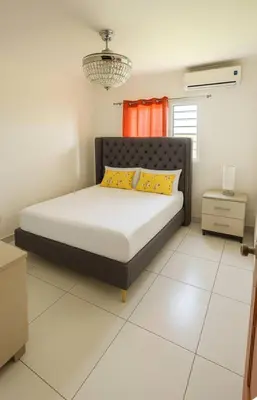 a bedroom with a bed with yellow pillows at Palma Real Near Cibao Airport in Santiago de los Caballeros