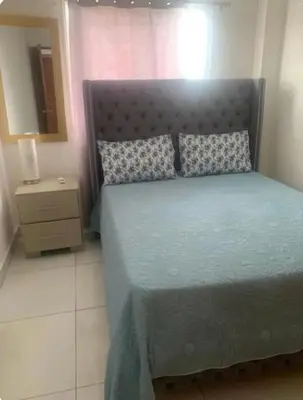 a bedroom with a bed with a blue comforter at Palma Real Near Cibao Airport in Santiago de los Caballeros