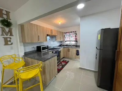 a kitchen with wooden cabinets and a black refrigerator at Beautiful residential area near Avenida España in Los Mameyes