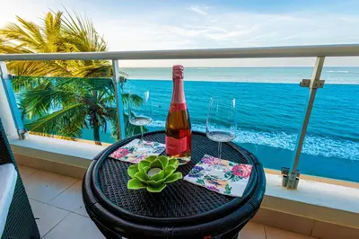 a bottle of wine sitting on a table on a balcony at Cozy Beach Front Apt, King Bed. in Cabarete