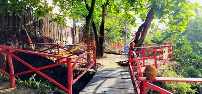 a wooden bridge with a red fence and trees at Jarabacoa River Club & Resort in Jarabacoa