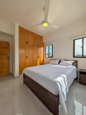 a bedroom with a large bed and wooden cabinets at Prado Garden Hotel in Monte Plata