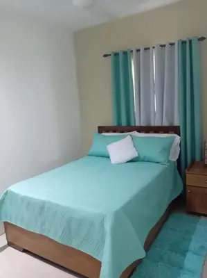 a bedroom with a bed with blue sheets and a window at Casa Brisa del Río in Las Terrenas