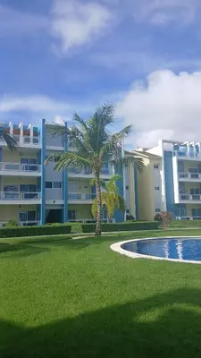 a large apartment building with a palm tree and a pool at Eden Caribe Punta Vana in Punta Cana