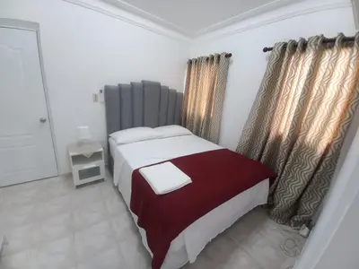 a bedroom with a large bed with a red blanket at Casa Petter og Maria first floor in Santiago de los Caballeros