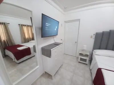 a bedroom with a tv and a bed and a mirror at Casa Petter og Maria first floor in Santiago de los Caballeros
