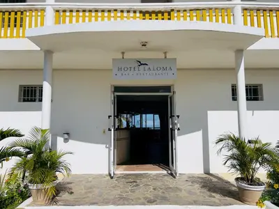 a white building with a door with a sign on it at Hotel La Loma in Miches