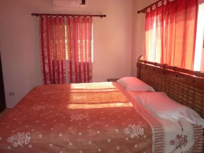 a bedroom with a large bed with red curtains at Villa near the beach in Cabarete
