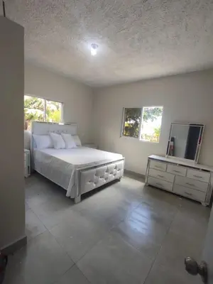 a bedroom with a large white bed and a dresser at Hermosa casa de campo in Juana Vicenta