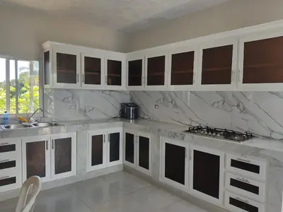 a kitchen with white cabinets and marble counter tops at Hermosa casa de campo in Juana Vicenta