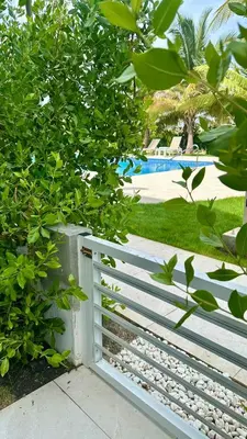 a white fence with a pool in the background at A104 - PRADOS · Peaceful 2BR Poolside Retreat • Punta Cana Getaway in Punta Cana