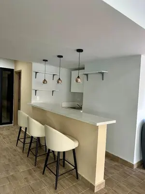 a kitchen with a bar with white chairs and lights at Moderno 1 Habitación Cerca Avenida Churchill in Santo Domingo