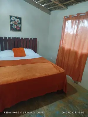 a bedroom with a bed with an orange blanket and a window at Parador tropical Raysa in Las Galeras