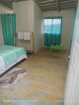 a bedroom with a concrete floor and blue curtains at Parador tropical Raysa in Las Galeras