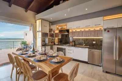 a kitchen with a table and chairs and a kitchen with the ocean at Increíble ático de lujo con impresionantes vistas in Puerto Plata