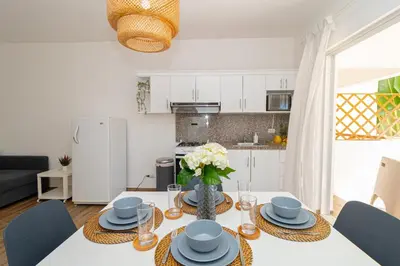 a kitchen and living room with a table with plates and flowers at Luxury 1 BR at Paraiso Residence Bayahibe in Bayahibe