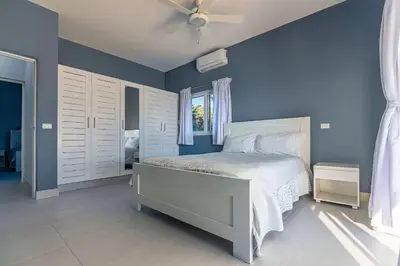 a blue bedroom with a bed and a ceiling fan at Villa real con piscina panorámica para más de 14 huéspedes in Sosúa